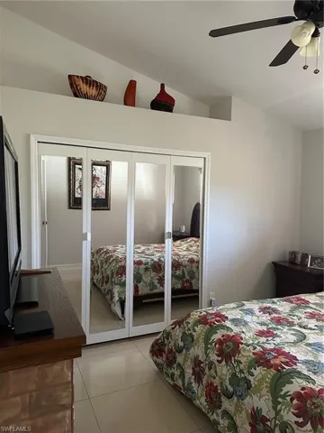 Bedroom featuring a ceiling fan, light tile patterned flooring, and lofted ceiling