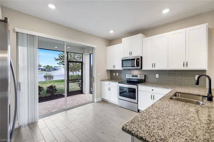 Kitchen featuring stainless steel appliances, a water view, white cabinetry, light stone countertops, and recessed lighting