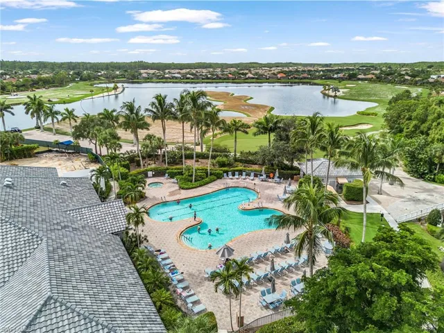 Community pool with a water view, a patio, and view of golf course