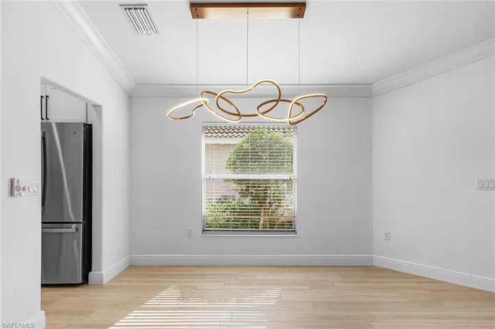 Dining area with modern light fixture, crown molding and luxury vinyl wood-like flooring.