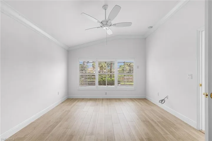 Main bedroom with crown molding, lofted ceiling, light wood-type flooring, and ceiling fan, plantation shutters, view of the pool.
