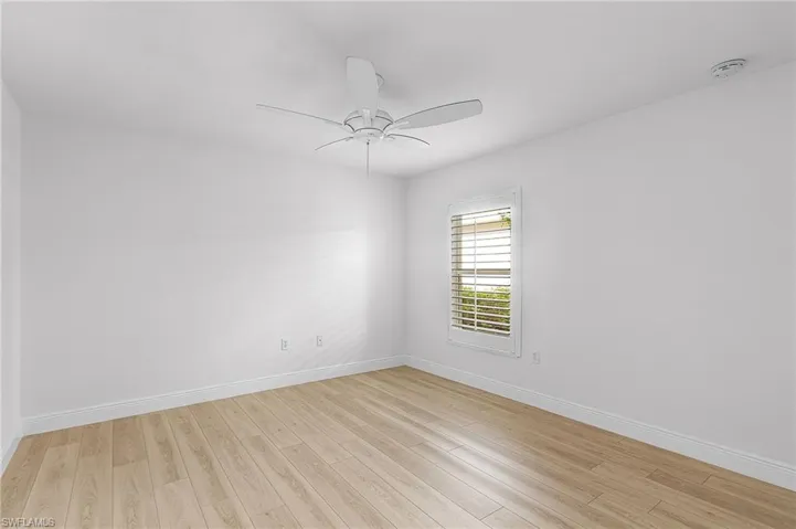 Spacious guest bedroom with plantation shutter, ceiling fan, and luxury vinyl flooring.
