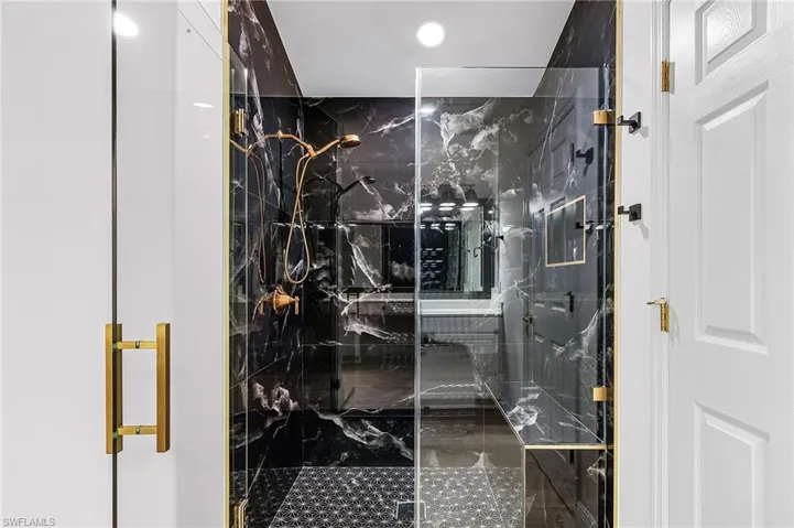 Bathroom featuring a marble finish shower with bench seat.