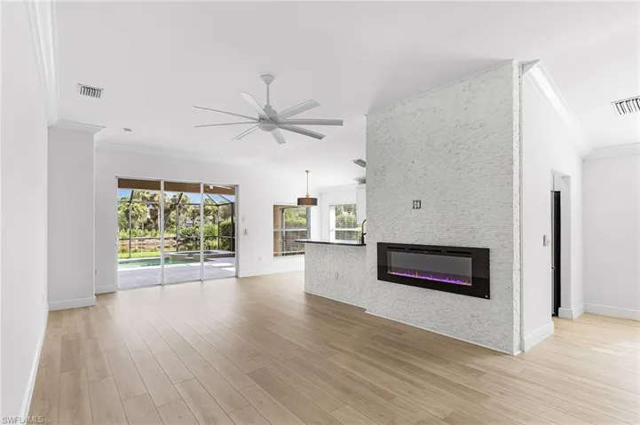 Great room featuring crown molding, a large electric fireplace, ceiling fan, light wood-style floors, open style floor plan.