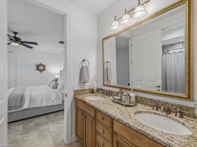 Ensuite bathroom featuring double vanity, curtained shower, and a ceiling fan