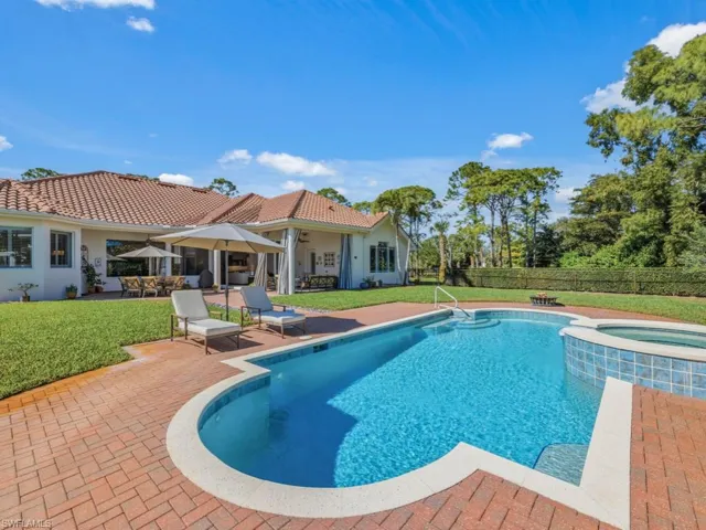 View of pool featuring a patio area, a pool with connected hot tub, a fenced backyard, and outdoor dining space