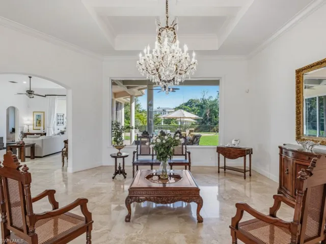 Living area with ceiling fan, arched walkways, marble tiled flooring, ornamental molding, and a chandelier