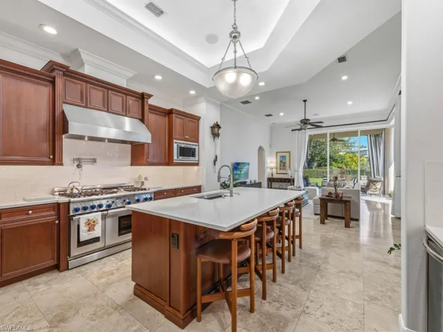 Kitchen with stainless steel appliances, under cabinet range hood, arched walkways, decorative light fixtures, and decorative backsplash