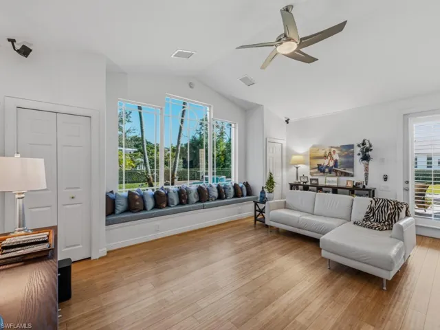 Living area featuring ceiling fan, light wood-type flooring, and lofted ceiling