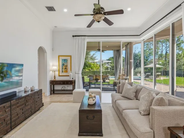 Living area featuring a ceiling fan, arched walkways, and ornamental molding