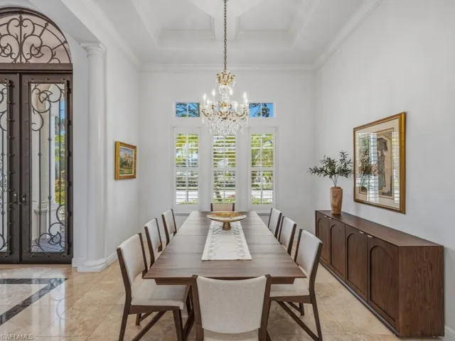 Dining space featuring ornate columns, a chandelier, french doors, and crown molding