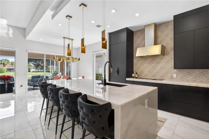 Kitchen with dark cabinetry, modern cabinets, a breakfast bar, pendant lighting, and a spacious island
