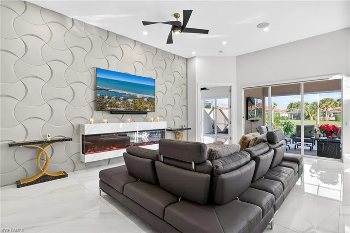 Living area with an accent wall, wallpapered walls, marble tiled floors, ceiling fan, and recessed lighting
