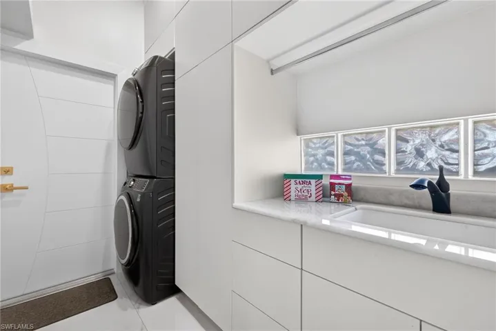 Laundry area featuring estacked washer and dryer and light tile patterned floors