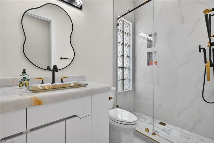 Bathroom featuring vanity and a marble finish shower