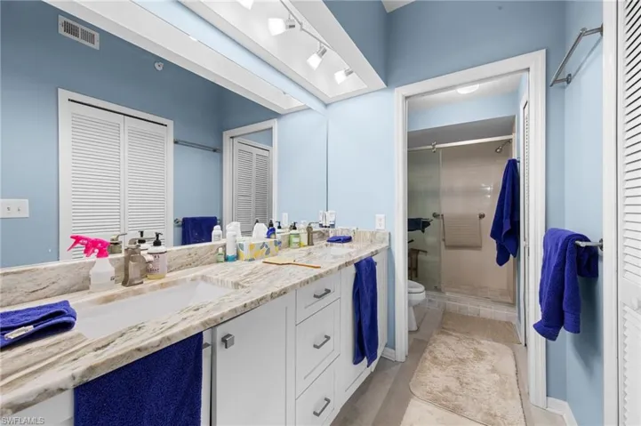 Bathroom with a closet, double vanity, a stall shower, and tile patterned flooring