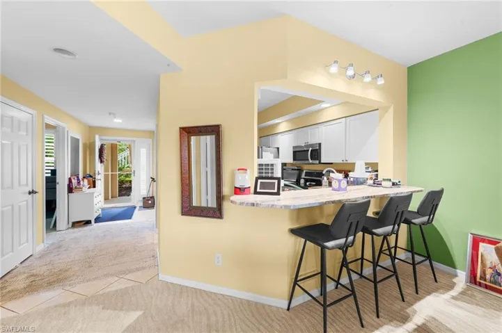 Kitchen with light carpet, a kitchen breakfast bar, stainless steel microwave, a peninsula, and white cabinets