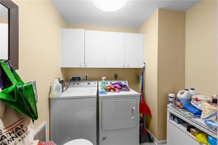 Washroom with washer and clothes dryer and cabinet space