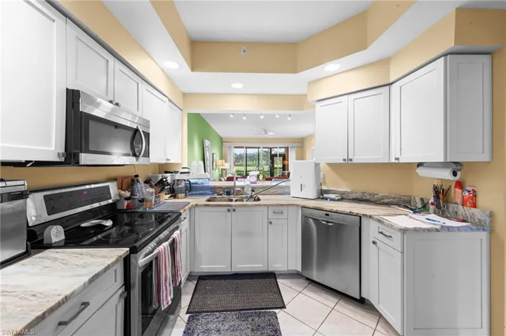 Kitchen featuring stainless steel appliances, light tile patterned floors, recessed lighting, white cabinets, and light stone countertops