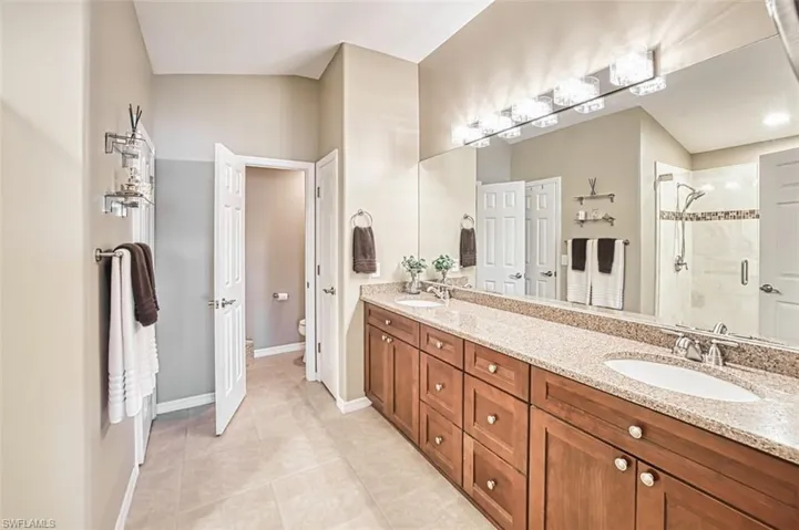 Full bath featuring double vanity, a stall shower, and light tile patterned floors