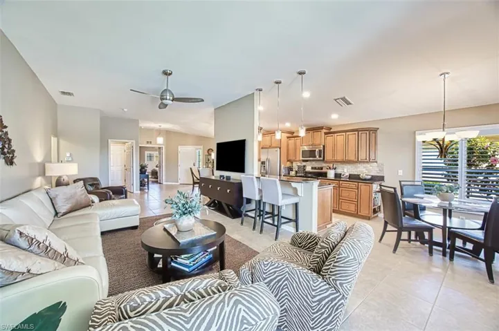 Living room with a chandelier, light tile patterned flooring, a ceiling fan, recessed lighting, and lofted ceiling
