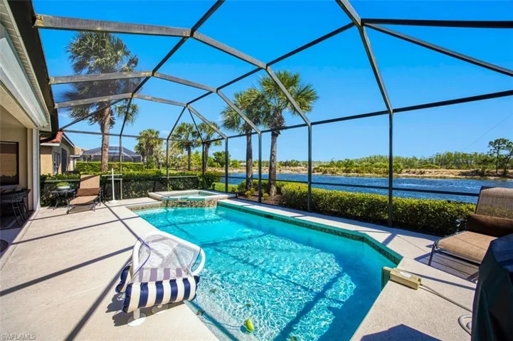 View of swimming pool featuring a sunroom, a patio, a lanai, a pool with connected hot tub, and a water view