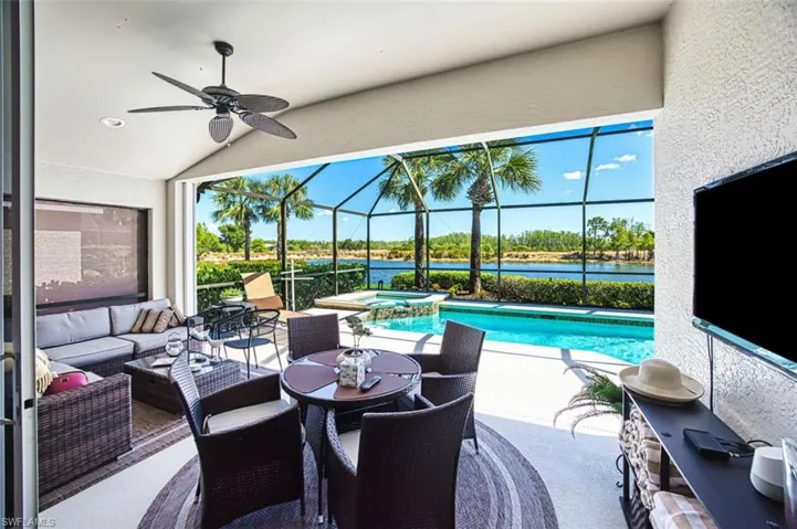 View of swimming pool featuring a sunroom, a patio, a pool with connected hot tub, ceiling fan, and glass enclosure