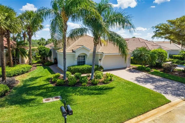 View of front of property with decorative driveway, an attached garage, stucco siding, a front lawn, and a tile roof