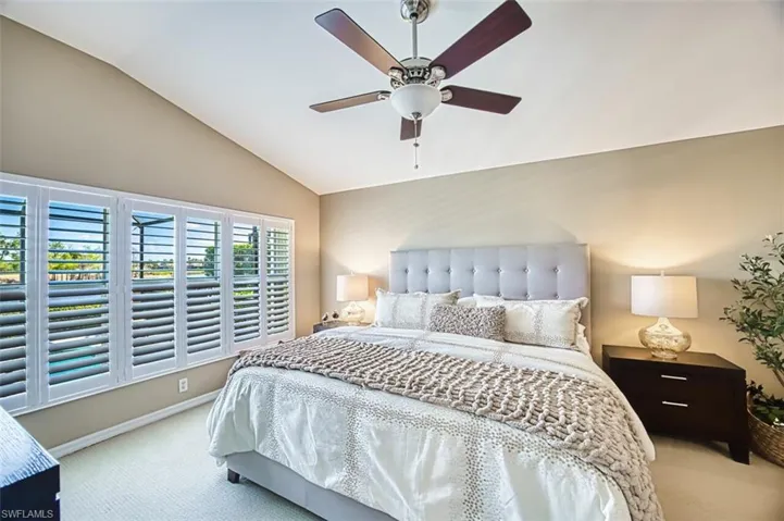 Carpeted bedroom with vaulted ceiling and ceiling fan