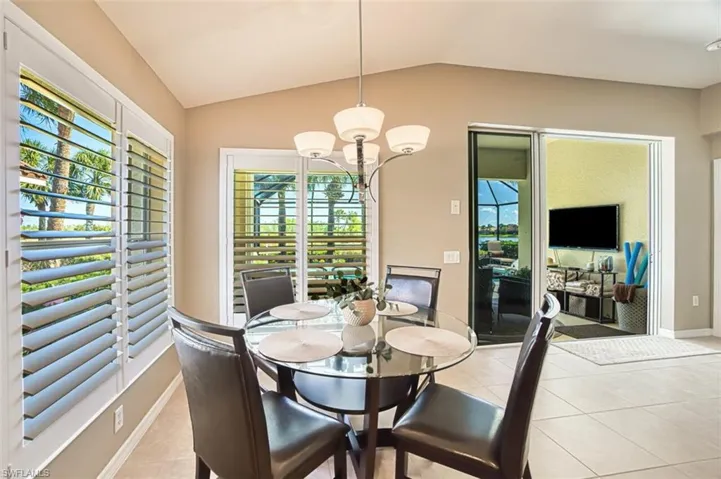 Dining space featuring light tile patterned floors, vaulted ceiling, and a chandelier