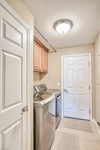 Laundry area with washer and dryer, cabinet space, and light tile patterned floors