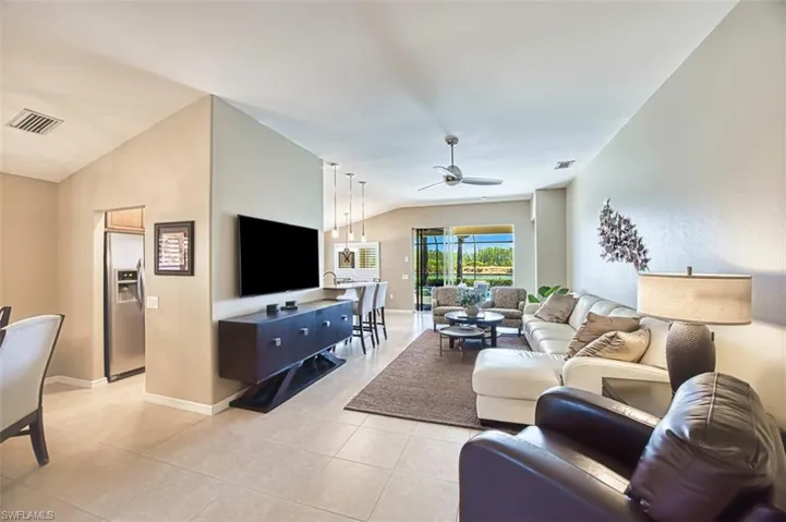 Living room with vaulted ceiling, light tile patterned flooring, and ceiling fan