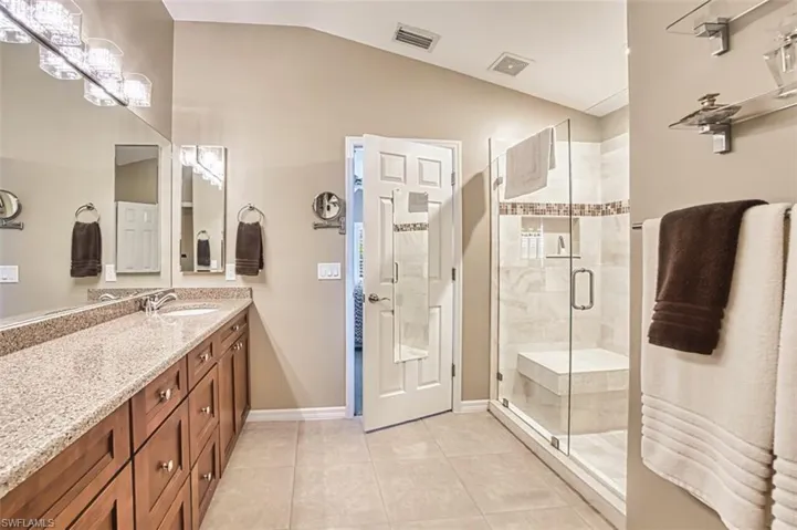 Bathroom featuring light tile patterned floors, vanity, and a shower stall