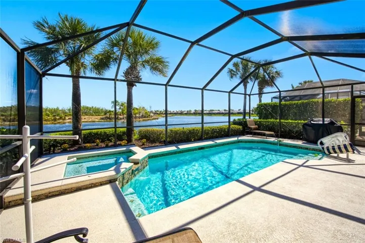 View of pool with a water view, a sunroom, glass enclosure, a pool with connected hot tub, and a patio