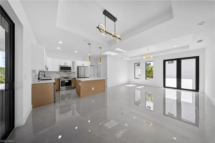Kitchen featuring dual tone cabinetry, a kitchen island, open floor plan, a tray ceiling, and stainless steel appliances