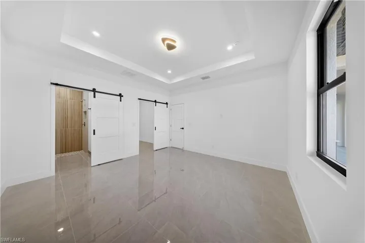 Unfurnished bedroom featuring a barn door and baseboards