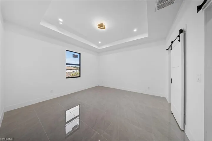 Unfurnished bedroom with a barn door, light tile patterned flooring, and recessed lighting