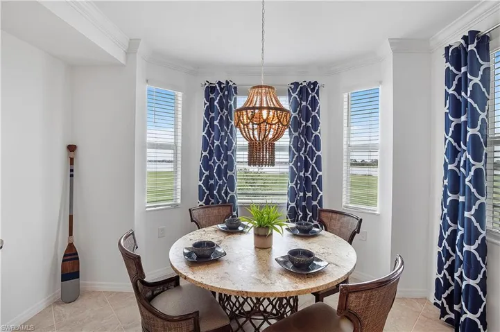 Dining area featuring light tile patterned flooring, ornamental molding, and a healthy amount of sunlight