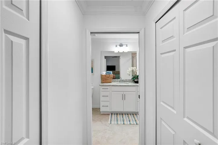 Hallway with sink, crown molding, and light tile patterned floors