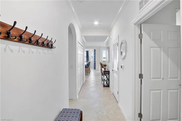 Hall with ornamental molding and light tile patterned flooring