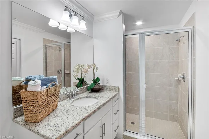 Bathroom featuring vanity, crown molding, and an enclosed shower