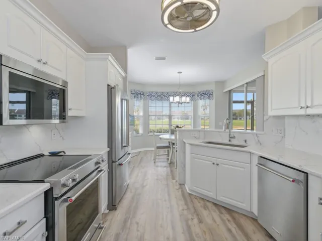 Kitchen with white cabinets, a sink, appliances with stainless steel finishes, and a chandelier