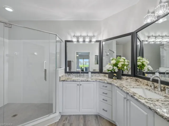 Full bath with a stall shower, double vanity, wood finished floors, and a sink