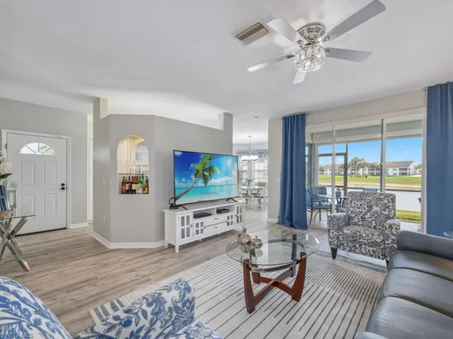 Living area with baseboards, ceiling fan with notable chandelier, light wood-style floors, and visible vents