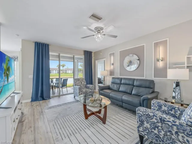Living room with baseboards, light wood-style flooring, visible vents, and ceiling fan