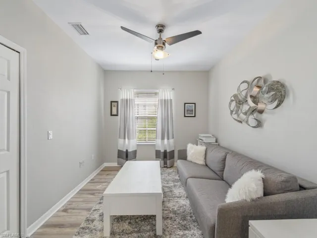 Living room featuring baseboards, light wood-style floors, ceiling fan, and visible vents