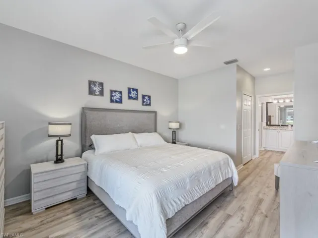 Bedroom featuring baseboards, ensuite bath, light wood finished floors, visible vents, and a closet