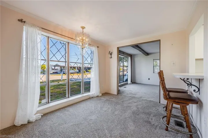 Unfurnished dining area with a chandelier, carpet, and crown molding