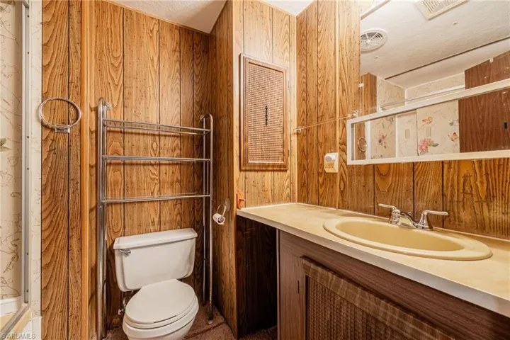 Bathroom with wooden walls, toilet, and vanity