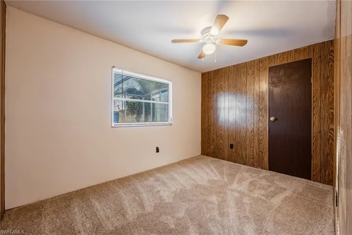 Unfurnished bedroom room with wooden walls, ceiling fan, and carpet flooring